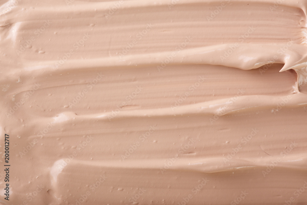 Fototapeta premium Beige liquid foundation makeup as a background. Top view. Flat lay pattern