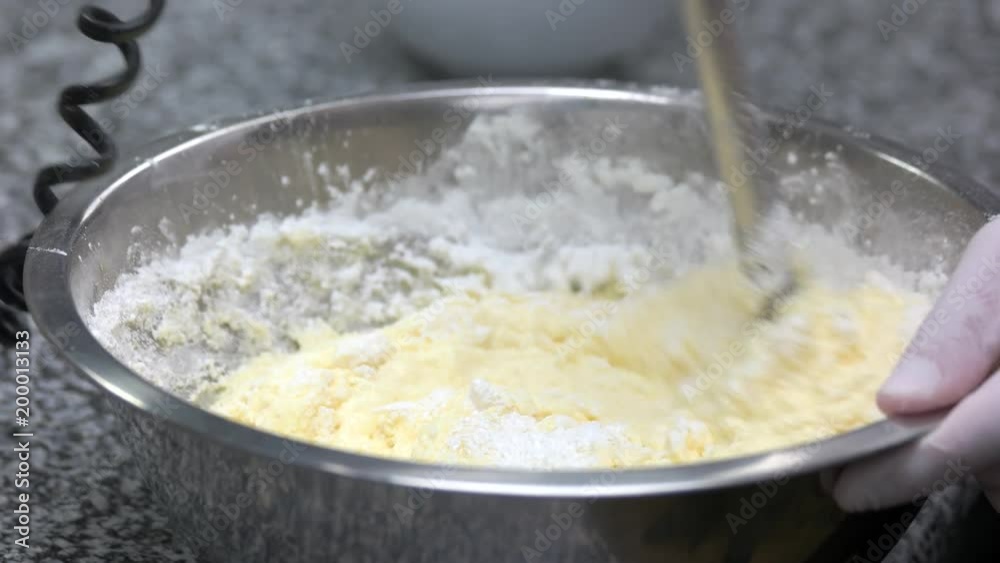 Kneading a thick dough with white flour. Mixing dough and flour. Flour changing colour while stirring.