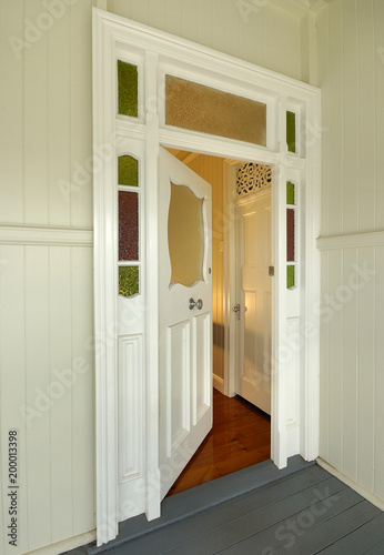 Door to old colonial style wooden home, slightly open with warm interior light in Queensland Australia. photo