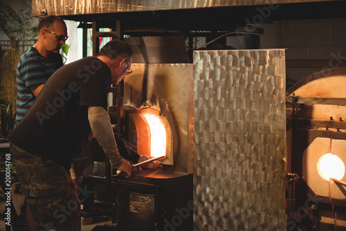 Team of glassblowers heating a glass in furnace photo