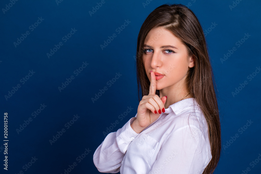 Young beautiful woman has put forefinger to lips as sign of silence Young beautiful woman has put forefinger to lips as sign of silence