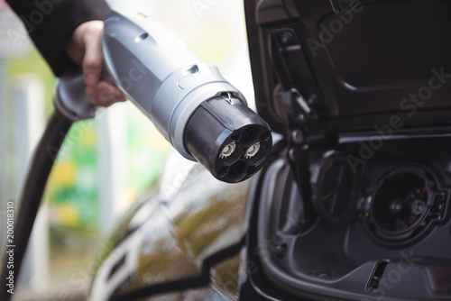 Man charging electric car at electric vehicle charging station photo