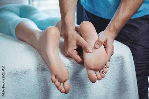 Male physiotherapist giving foot massage to female patient
