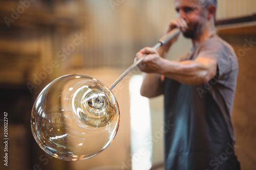 Glassblower shaping a glass on the blowpipe photo