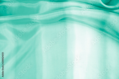 The texture of the satin fabric of green color for the background 
