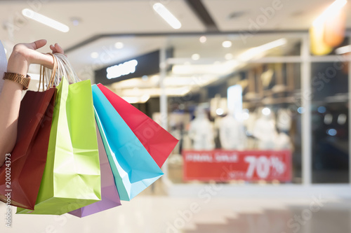 Woman with shopping bags in shopping mall, Sale banner in shop window, consumerism and sale concept.