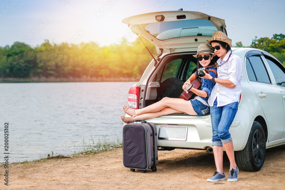Φωτογραφία Couple of traveler sitting on hatchback of car and looking at the picture on camera near the lake during holiday