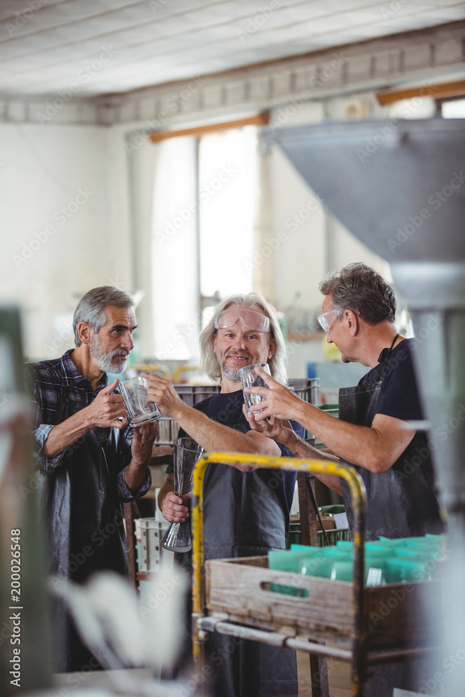 Glassblowers examining glass vase in glassblowing factory Glassblowers examining glass vase in glassblowing factory
