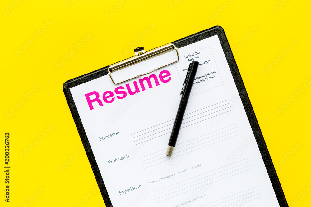 Looking for work concept. Resume on padwith on yellow background top view space for text Looking for work concept. Resume on padwith on yellow background top view space for text