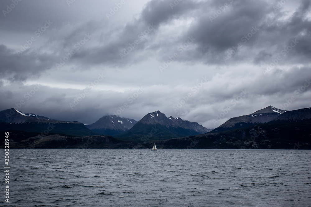 sailboat sailind before landscape of Patagonian mountains, taken from the beagle channe. Ushuaia, patagonia