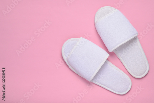 White hotel slippers on a pink background, top view, minimalist trend.