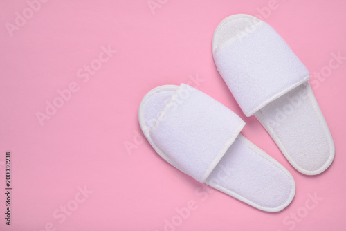 Fotografi White hotel slippers on a pink background, top view, minimalist trend