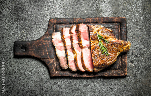 Grilled beef steak on a blackboard with spices.