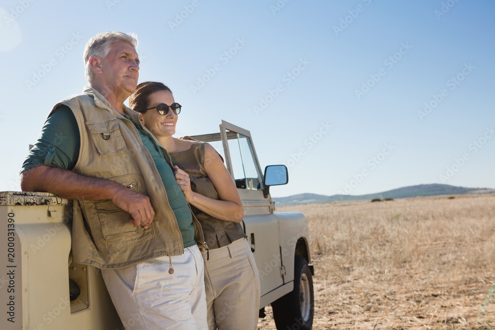 Couple looking away while standing by vehicle on field Couple looking away while standing by vehicle on field