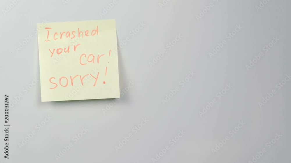 Closeup yellow sticker paper sheet with words i crashed your car, sorry on refrigerator. Closeup yellow sticker paper sheet with words i crashed your car, sorry on refrigerator.