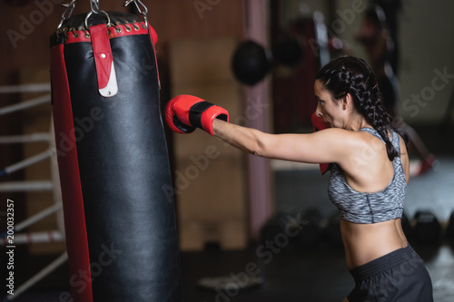 Female boxer practicing boxing with punching bag photo