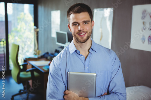 Portrait of male physiotherapist holding digital tablet