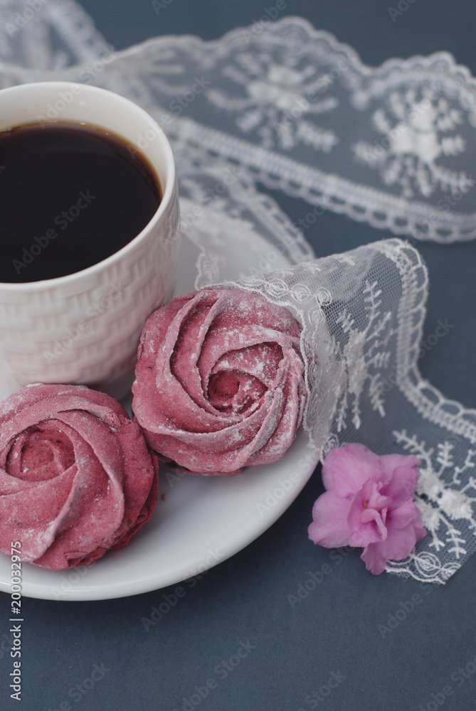 Sweet Pink Meringues and Cup of Coffee on Blue Gray background with Orchid Flowers and Lace. Spring Background with copy space. Breakfast. Sweet Pink Meringues and Cup of Coffee on Blue Gray background with Orchid Flowers and Lace. Spring Background with copy space. Breakfast.