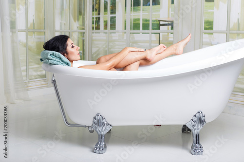 beautiful young woman touching her leg while enjoying luxurious bath