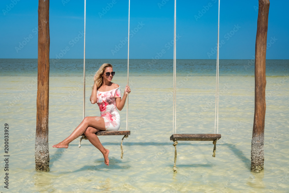Blonde girl on a beach swing