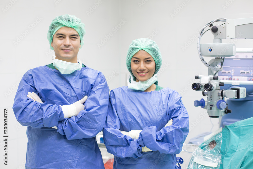 In a Modern Operating room Doctor and team looking to camera with smile. In a Modern Operating room Doctor and team looking to camera with smile.
