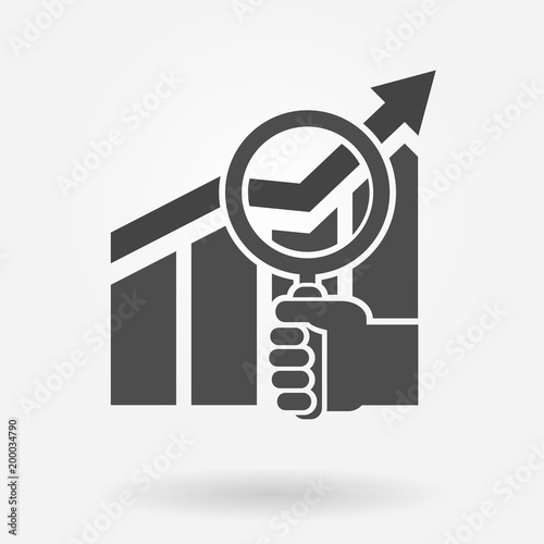 Business and stock market analysis icon concept. Hand holding magnifying glass over a chart