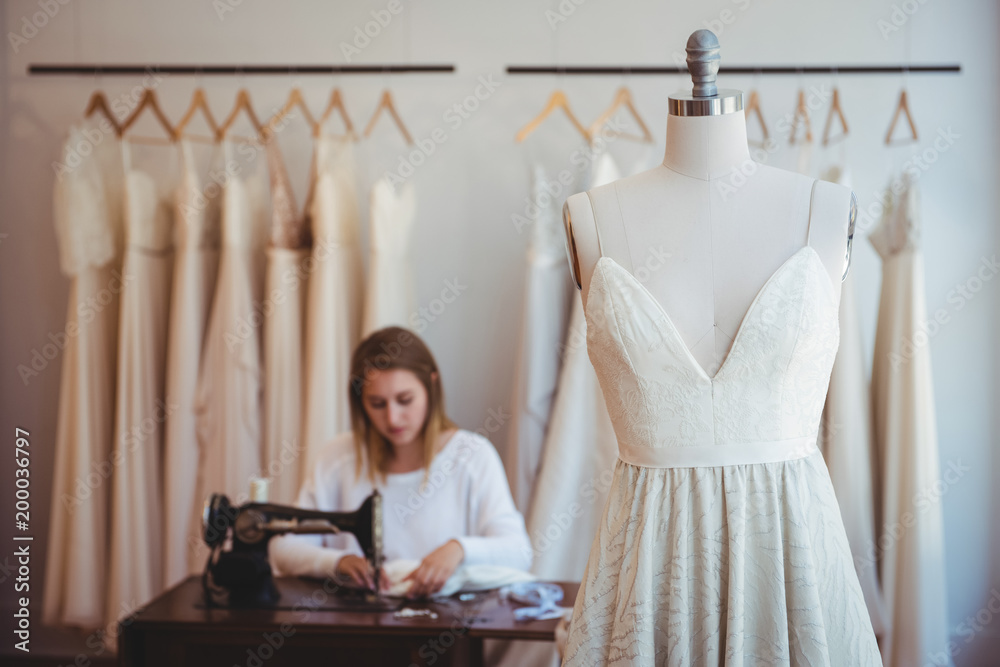 Couture hanging on mannequin with fashion designer working in background Couture hanging on mannequin with fashion designer working in background