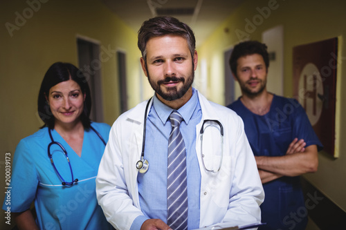 Portrait of doctor standing with nurse and ward boy in corridor photo
