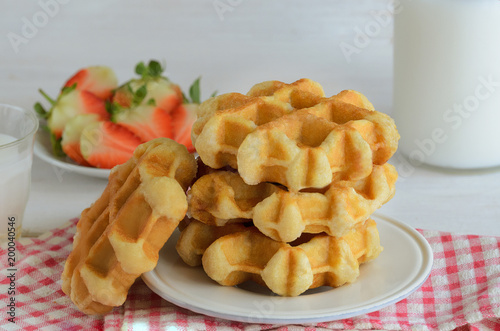 Fresh belgian waffles  served wirh strawberry and milk for breakfast. Delicious homemade dessert background.