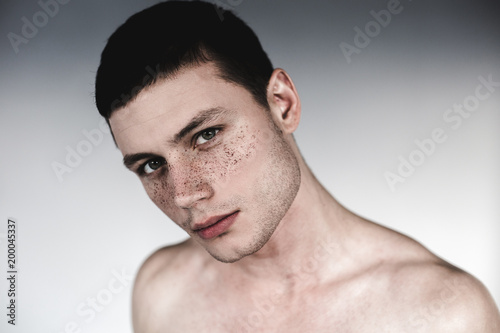 Portrait of relieved undressed male with settled eye watching at camera