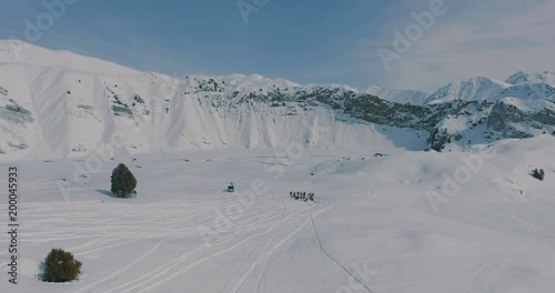 Aerial overflight over a helicopter, a group of skiers and snowboarders in the winter mountains photo