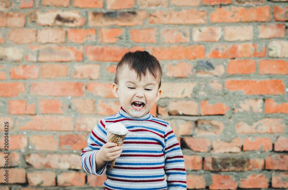 little cute boy eating ice cream three years very appetizing, amid nature, green grass