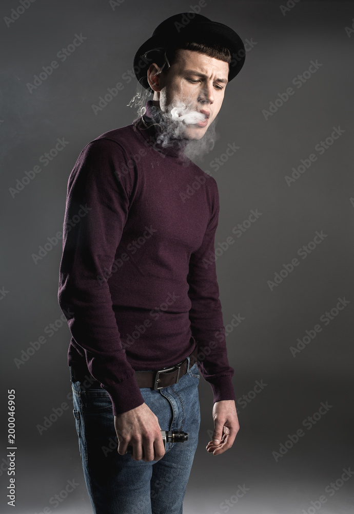 Portrait of melancholic man locating in fume while keeping gadget in hand. Unhappy guy concept