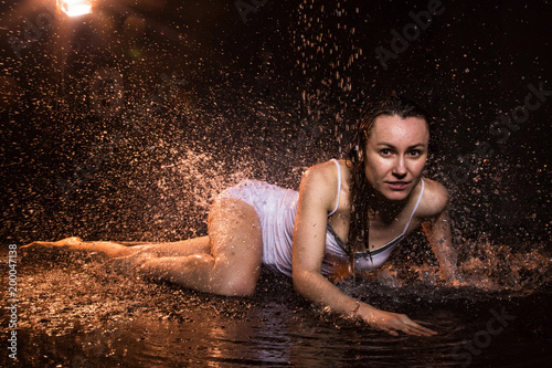 Girl in white dress in water in a dark water in pool in studio and dark background