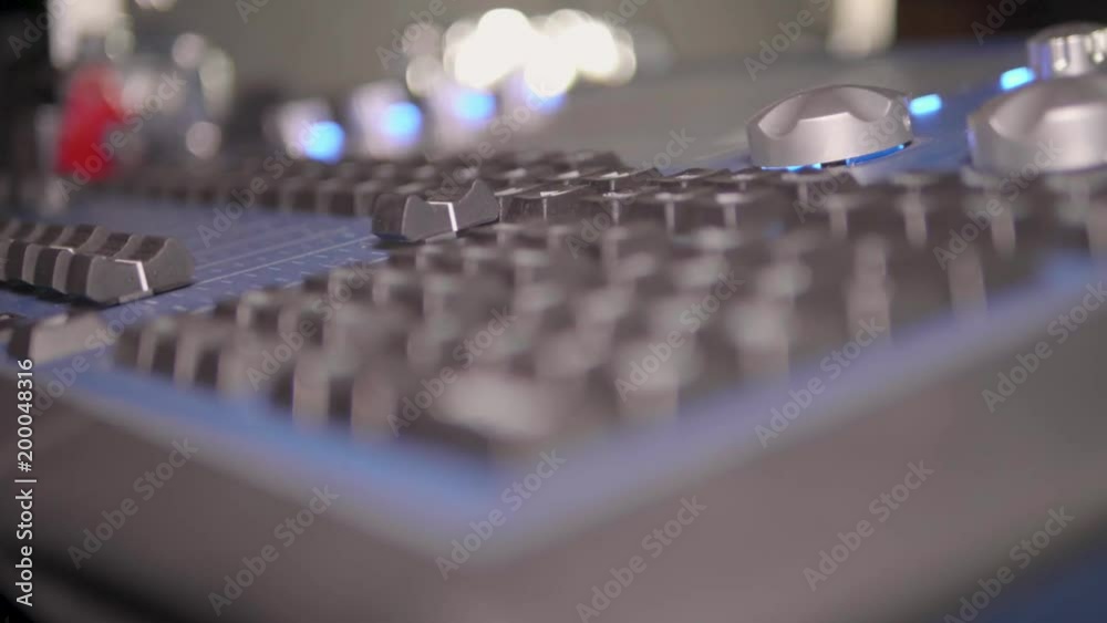 Roll focus close up across a media control console at an outdoor night event