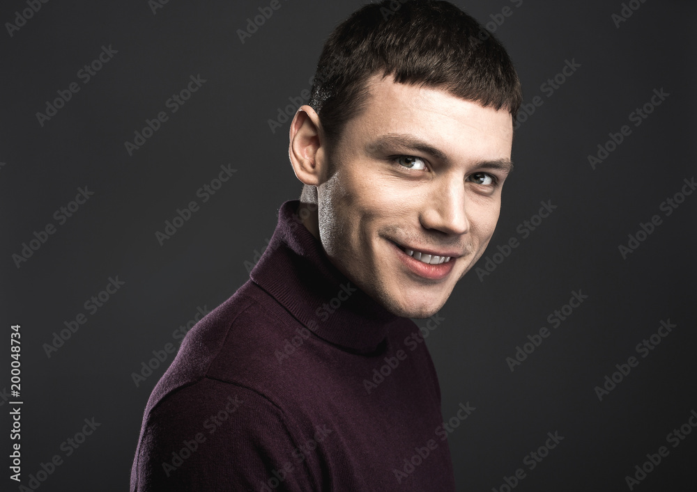 Naklejka premium Portrait of cheerful young man with friendly smile isolated on black background. Happiness concept