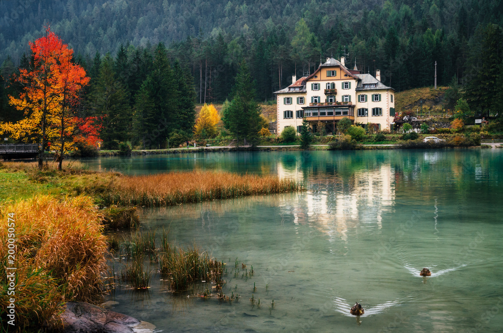 Dobbiaco Lake or Toblacher in Dolomites with hotel restaurant on coast in autumn