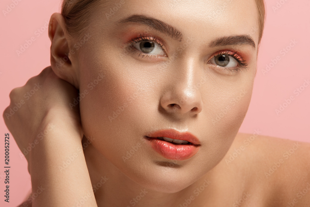 Close up of female face with soft derma and light makeup. She is looking at camera with tranquility. Isolated on rose background Close up of female face with soft derma and light makeup. She is looking at camera with tranquility. Isolated on rose background