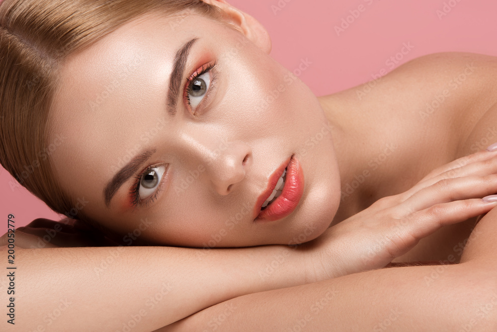Close up portrait of good looking girl with naked shoulders. She is relaxing on her arm and staring at camera with calmness. Isolated on rose background Close up portrait of good looking girl with naked shoulders. She is relaxing on her arm and staring at camera with calmness. Isolated on rose background