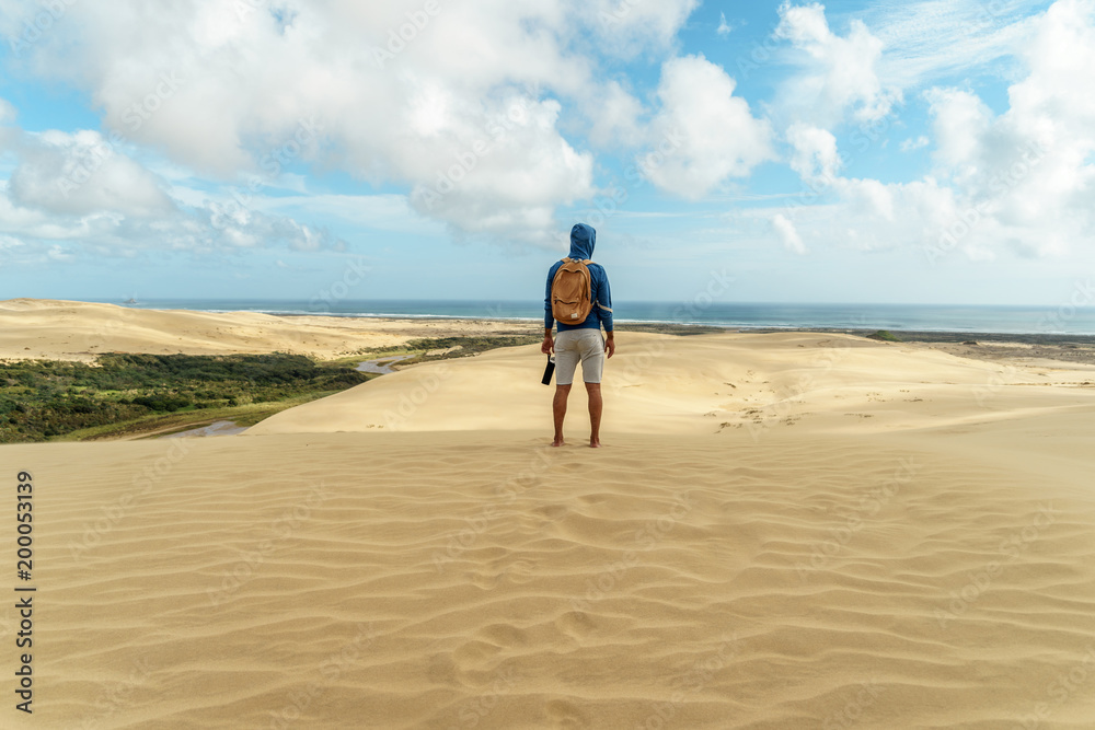 rear view of lonely hiker standing on sand dune and looking away, Giant Sand Dunes, New Zealand