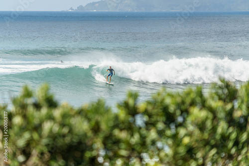 Photography man riding on waves with surfboard on cloudy day, Leigh beach, New Zealand