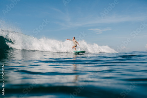 handsome sportsman riding waves on surfboard on sunny day