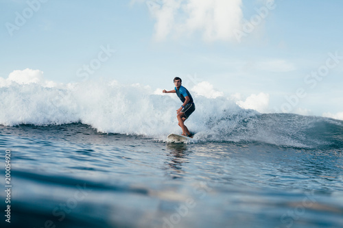 handsome young man in wetsuit surfing on sunny day