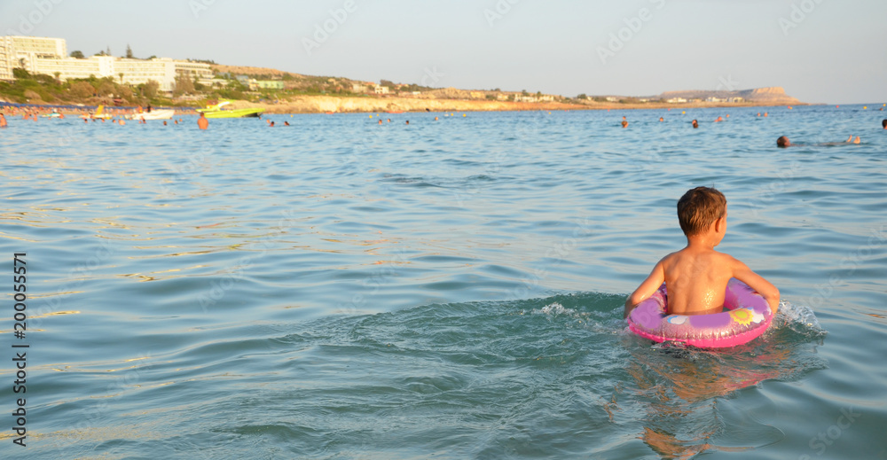 A little boy swimming in the sea. Happy child playing, swimming in the sea with rubber ring. summer vacation concept