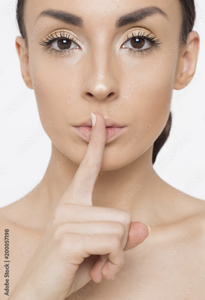 Close up Photo of a beautiful smiling female face with clean and fresh skin, the girl puts a finger to her lips. Close up Photo of a beautiful smiling female face with clean and fresh skin, the girl puts a finger to her lips.