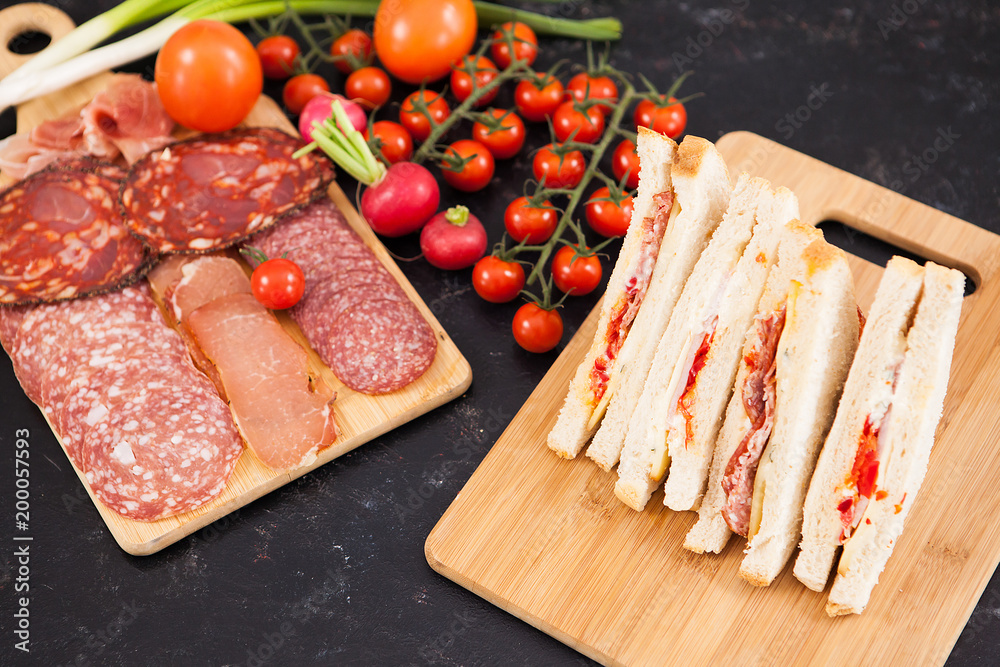 Club sandwiches with white bread and salami on wooden board Club sandwiches with white bread and salami on wooden board
