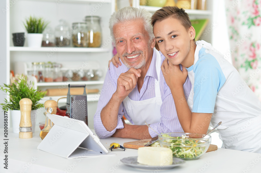 Senior man with grandson preparing dinner in kitchen Senior man with grandson preparing dinner in kitchen