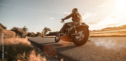 Fototapeta Mężczyzna jedzie sportster motocykl podczas zmierzchu.