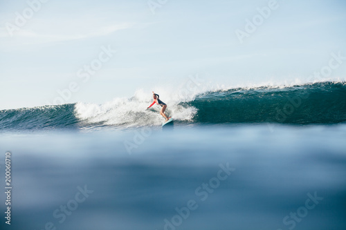 young woman in wetsuit surfing on ocean wave