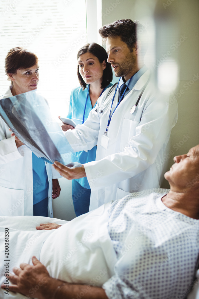 Doctors interacting over x-ray report with patient Doctors interacting over x-ray report with patient